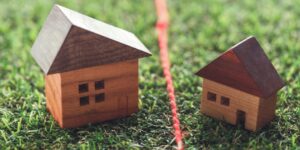 two small wooden house models with a string between them representing the boundary between properties