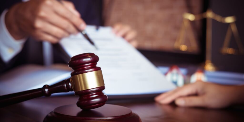 Judge and lawyer looking of paperwork with a gavel and block in the foreground and scales in the background