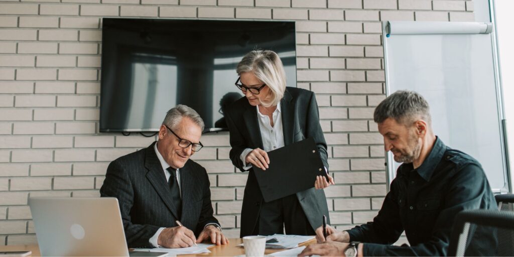 two business owners signing partnership agreements with a mediator
