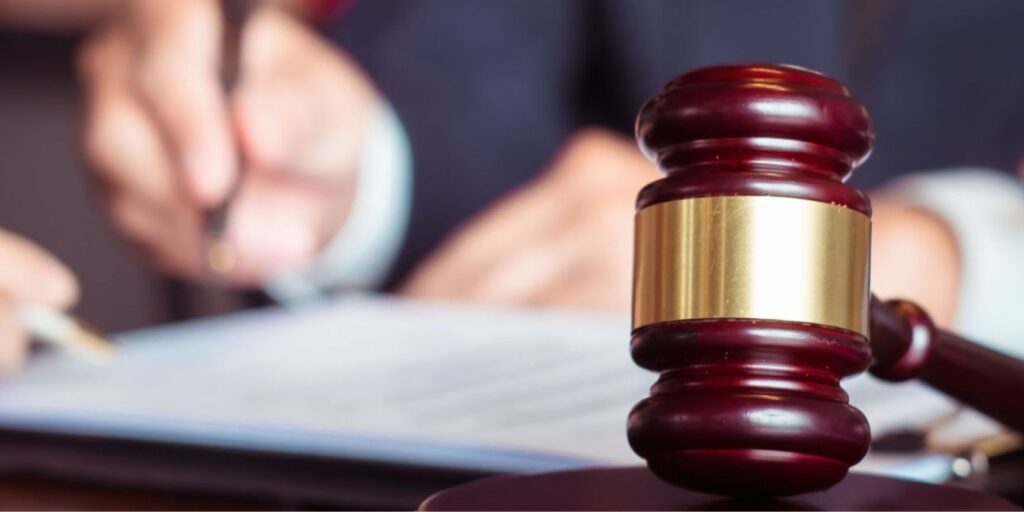 close-up of a judge’s gavel with a property division lawyer and client signing papers in the background