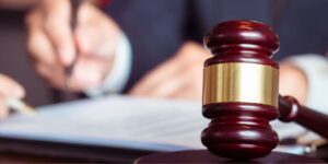 close-up of a judge’s gavel with a property division lawyer and client signing papers in the background