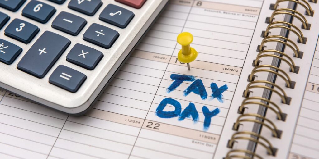 calendar with a calculator on top with a pin on Tax Day