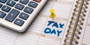 calendar with a calculator on top with a pin on Tax Day
