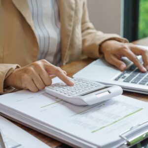 woman going over her finances with documents, laptop, and calculator